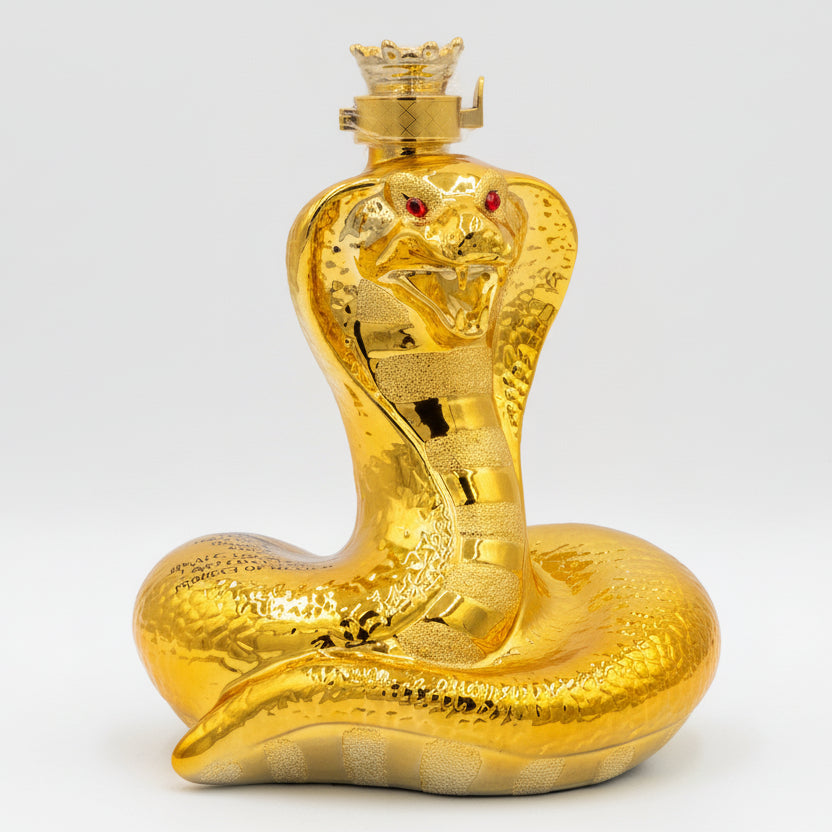 Gold snake-shaped bottle with red eyes on a white background