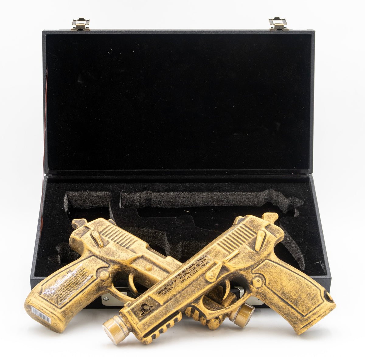 Two brass guns in a black case on a white background